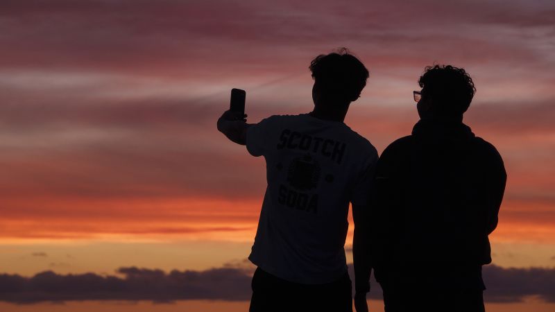 Students walking across a college campus with mobile phones