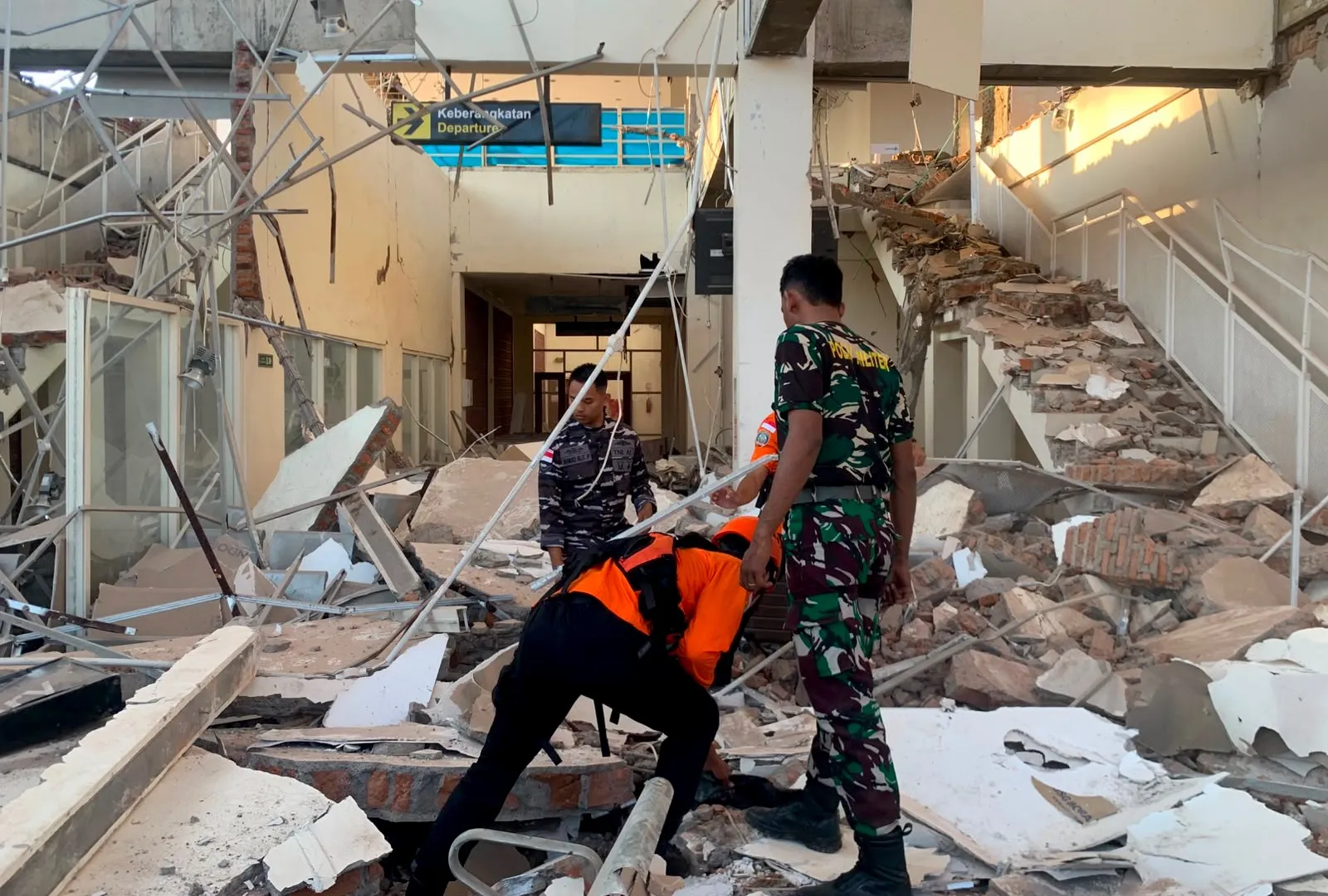 Emergency rescue teams and residents inspecting damaged buildings after a massive earthquake in Indonesia