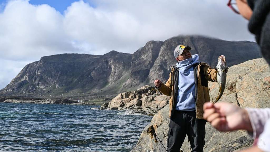 A migrant from the Philippines fishing by the fjords of Sisimiut, Greenland