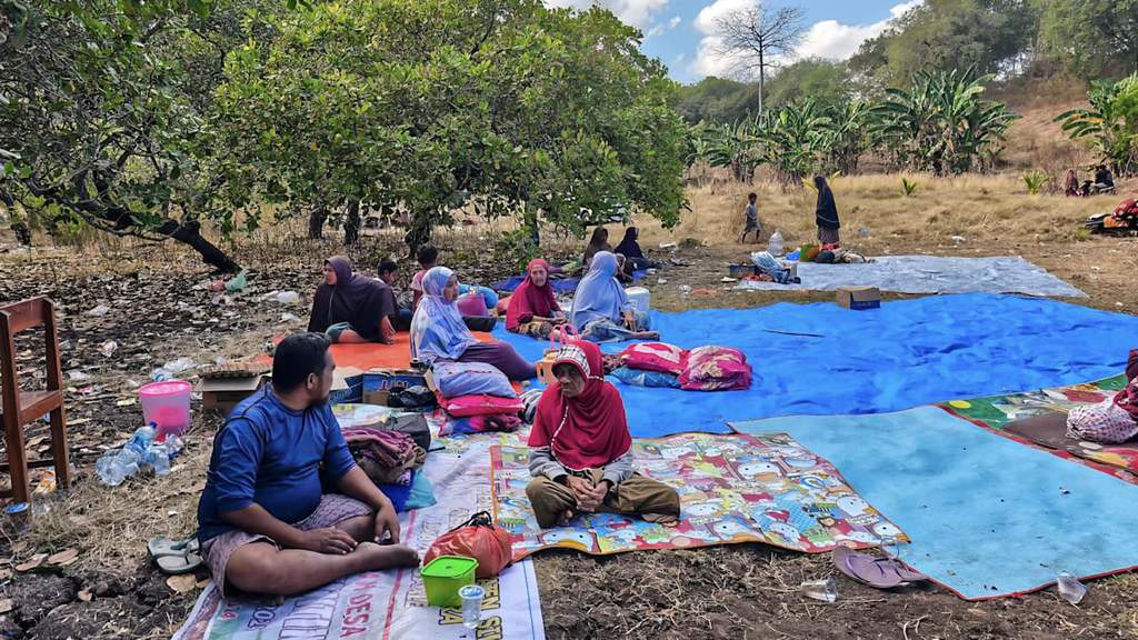 Villagers looking on after spending the night in an open field in Nangahale village in Sikka