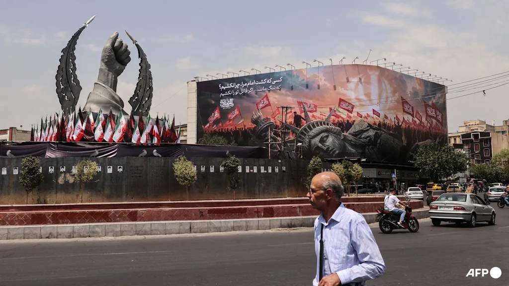 An Iranian man walking past an anti-US billboard at Enghelab Square in Tehran