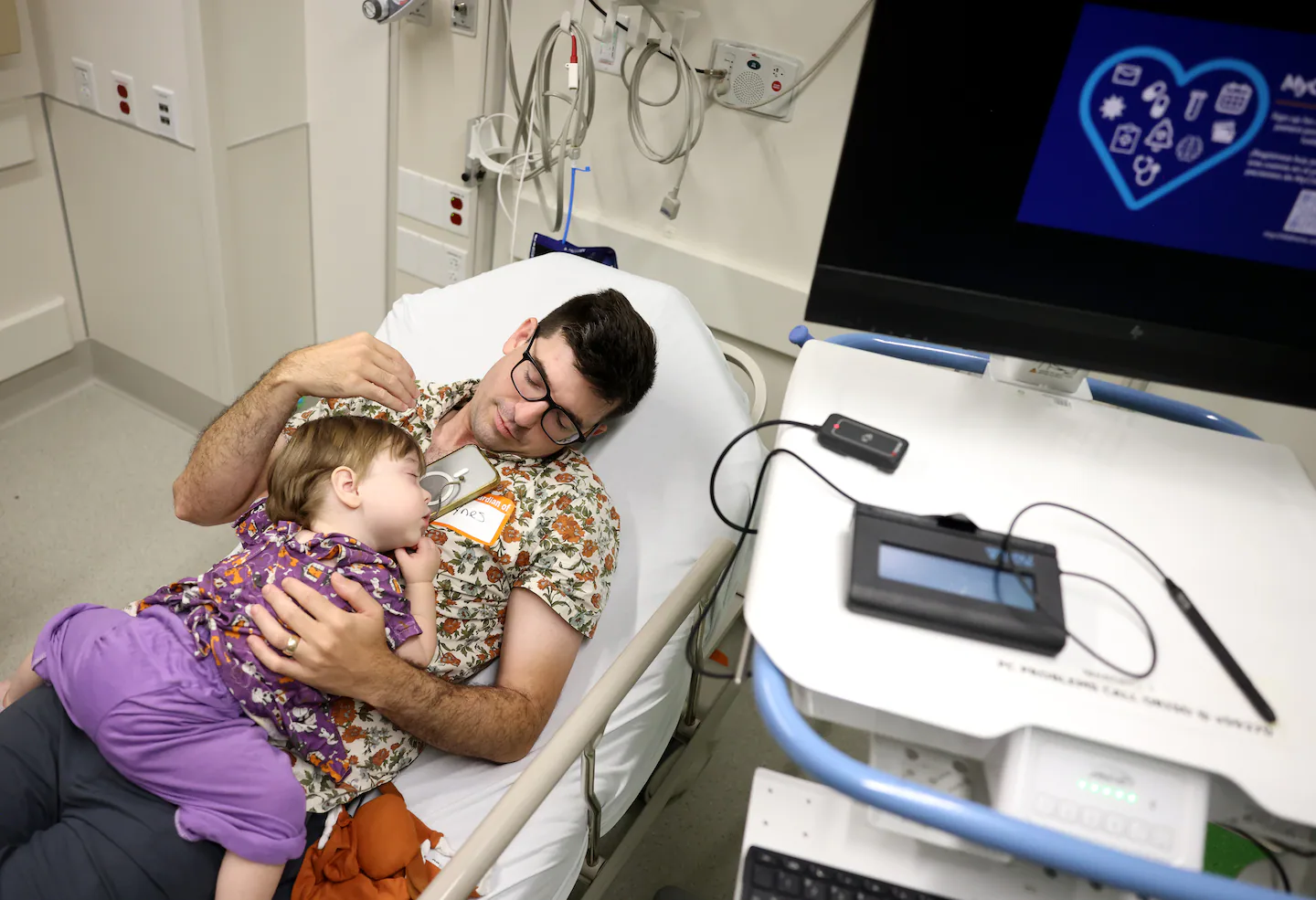 Young toddler sitting in a hospital bed looking through a children book